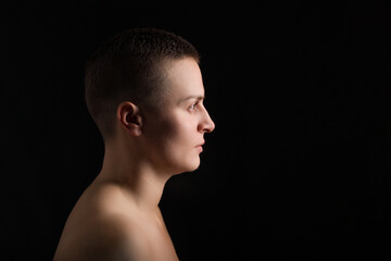 portrait of young woman with short hair and bare shoulder on black bakground