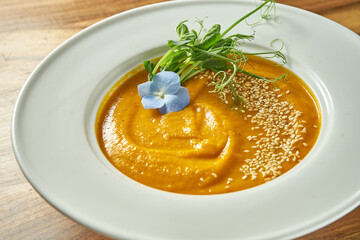 Vegetarian carrot ginger or pumpkin cream soup in a plate