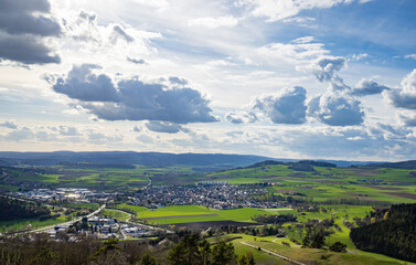 Obraz premium A town with roads, fields, pastures against the backdrop of silhouettes of hills and a cloudy sky