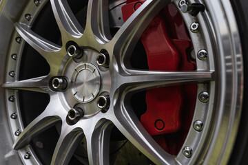 Close up of a polished alloy wheel of a sports car with red brake calipers