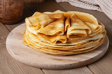 Thin pancakes on a wood plate. Homemade crepes, tasty food. Staple of yeast pancakes, traditional...