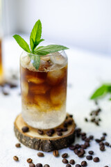 Cold summer cocktail with black coffee tonic mint and ice in glass on white background