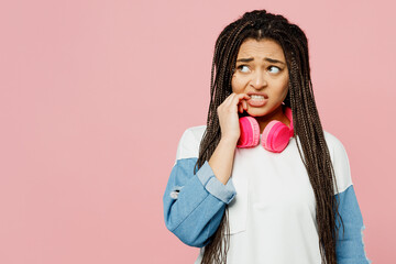 Young sad woman of African American ethnicity wear white sweatshirt casual clothes headphones look...