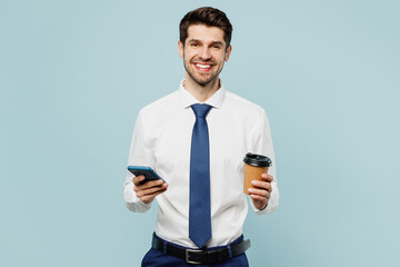 Young smiling employee business man corporate lawyer wear classic formal shirt tie work in office hold use area mobile cell phone drink coffee isolated on plain light blue background studio portrait.