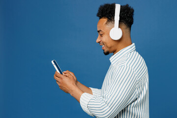 Side view young man of African American ethnicity wear casual clothes shirt headphones listen to...