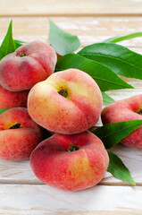 Fresh Flat Peaches, Chinese Saturn Donut Peaches with Leaves on Wooden Bright Background