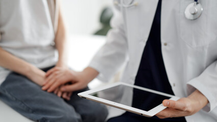 Doctor and child patient. The physician is holding tablet computer and reassuring a boy. The concept of ideal health in medicine