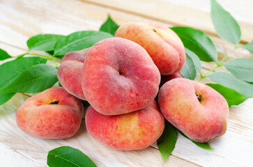 Fresh Flat Peaches, Chinese Saturn Donut Peaches with Leaves on Wooden Bright Background