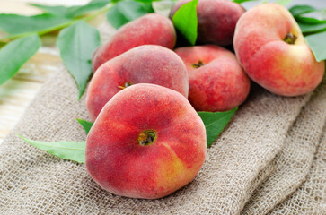 Fresh Flat Peaches, Chinese Saturn Donut Peaches with Leaves on Wooden Bright Background