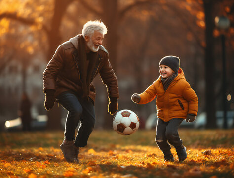 Grandfather and grandson playing football soccer in park, happy family