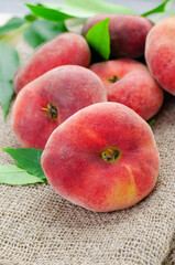 Fresh Flat Peaches, Chinese Saturn Donut Peaches with Leaves on Wooden Bright Background