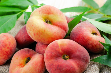 Fresh Flat Peaches, Chinese Saturn Donut Peaches with Leaves on Wooden Bright Background