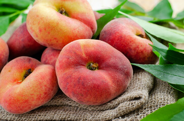 Fresh Flat Peaches, Chinese Saturn Donut Peaches with Leaves on Wooden Bright Background