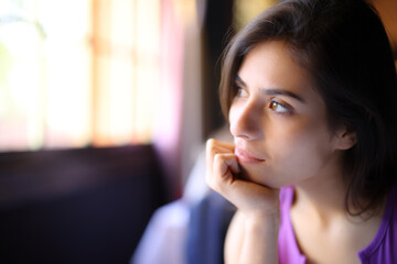 Pensive woman relaxing looking through a window