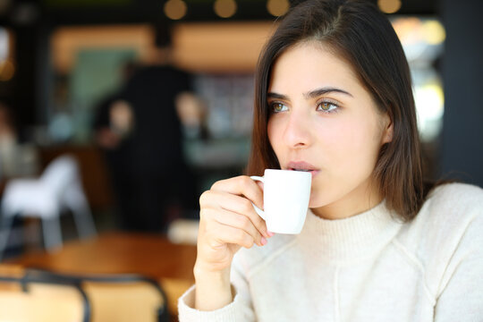 Serious woman drinking coffee in a bar alone