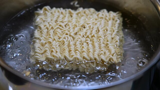 Cooking ramen noodles in boiling water in a pot