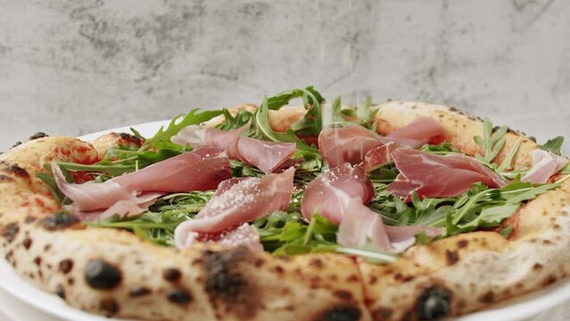 Prosciutto pizza with strachatella cheese, tomatoes, arugula leaves. Delicious Pizza with prosciutto parma ham, arugula salad rocket on white background with ingredients. Top view. Italian cuisine. 