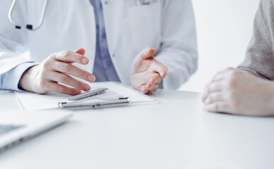 Fototapeta premium Doctor and patient discussing current health questions while sitting at the table in clinic office, only hands closeup. Medicine concept