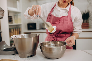 Portrait of confectioner woman In apron preparing to cook. Young girl whipping eggs in bow....