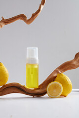 Front view of a yellow pump bottle unbranded with fresh lemon and dry twigs decorated on white...