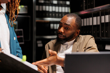 Private investigators examining information in crime matter report. African american detective...