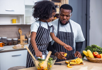 The family members happily and playfully prepare a bowl of various types of fruity and vegetable...