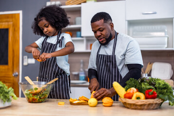 The family members happily and playfully prepare a bowl of various types of fruity and vegetable...