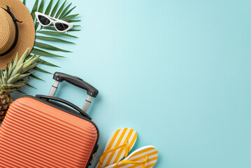 Summer escape to paradise. Overhead shot of orange suitcase, beach essentials, sunglasses, sunhat, flip-flops, ananas and palm leaves on a pastel blue background, perfect for text or promotions - obrazy, fototapety, plakaty
