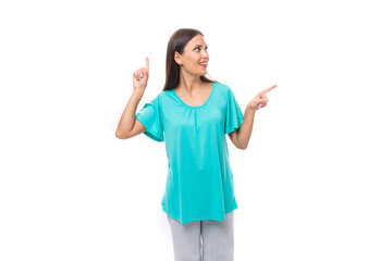 young pretty european woman with dark long hair dressed in a blue t-shirt points with her hands to the free space to insert advertising and text
