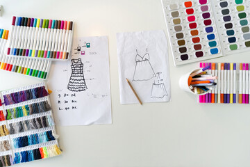 Fashion designer room. Pattern for cloth, silk thread color sample catalog, multi colored magic pens and sketching place on a large table. Top View