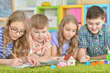 Naklejka premium Children lying on floor drawing with pencils
