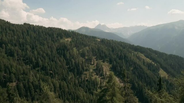 Fly through a forested landscape, unveiling a breathtaking view of the Dolomite mountains in this captivating FPV drone footage above Luzen village. LuPa Creative.