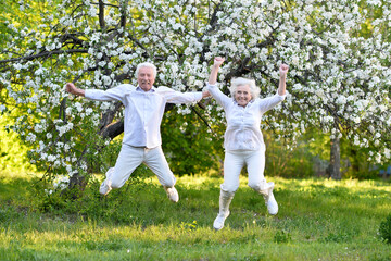 elderly couple jumps in summer in nature