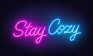 Stay Cozy neon lettering on brick wall background.