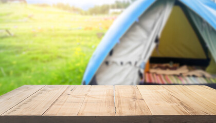 Wood table and Blurred camping and tents in forest.