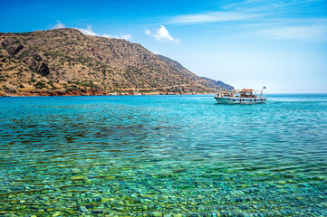 The sparkling azure waters merge seamlessly with the clear blue sky, creating a harmonious and captivating scene. Solitary boat gracefully adorning the horizon. 