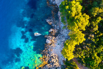 Rocky coast and sail yacht on the sea bay as a background. .Sea and waves from top view. Blue water background from top view. Top view from drone. Summertime vacation.