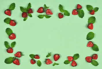 Frame made of  fresh ripe strawberries and green mint leaves on light green background. Top view, flat lay. Free copy space