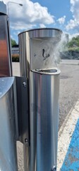 Smoke rising from inside metal cigarette disposal bin caught on fire.