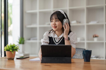 Online Learning. Cheerful School Student Girl Studying Using Digital Tablet and wireless headphones At Home