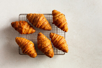 Croissants on a cooling rack on a beige background