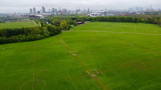 A lot of  empty football pitches or soccer pitches seen from the sky with a drone view and the London Stadium behind in Hackney Marshes