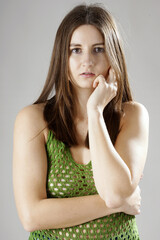 Portrait of a beautiful woman posing in a green knitted or crocheted top in photo studio in front of grey background