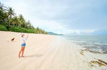 Fototapeta na wymiar Vacation and technology. Young woman taking photo of beautiful tropical beach on smartphone.
