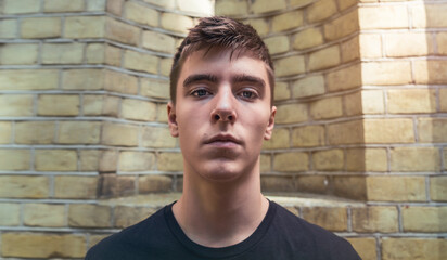 wide angle portrait of a handsome young man in front of a yellow brick wall