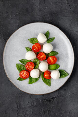 Caprese salad in the form of a Christmas tree. Festive tomato mozzarella and basil appetizer on light plate.