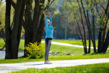 Woman standing on the park road with her arms up