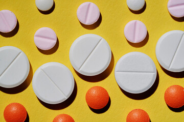 Medicine and drug concept. Pharmacy and health care. Close up of different tablets pattern on yellow background.
