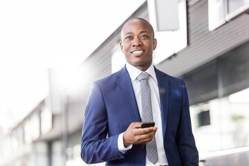 Smiling businessman with cell phone looking away