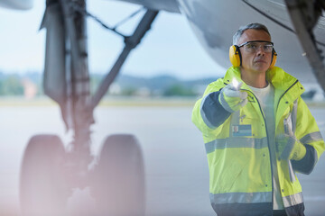Air traffic controller flashlight under airplane on airport tarmac